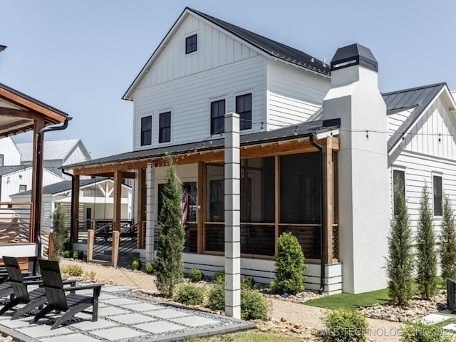 67 Lower Green Way Unit B, Carlton Landing, OK 74432 - rear view of house featuring board and batten siding, a patio area, a sunroom, metal roof, and a chimney