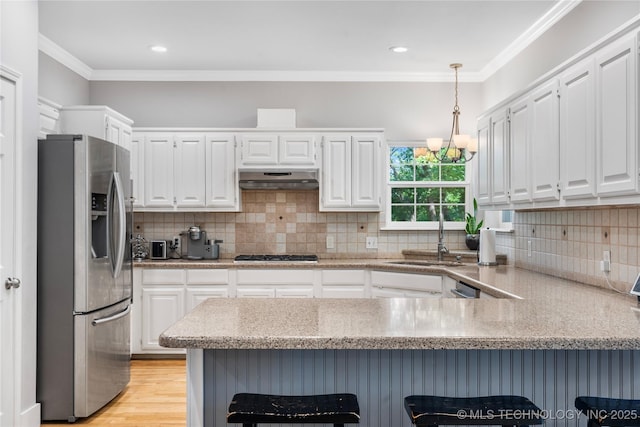11937 S 18th St, Jenks, OK 74037 - kitchen featuring appliances with stainless steel finishes, a sink, a peninsula, white cabinets, and under cabinet range hood