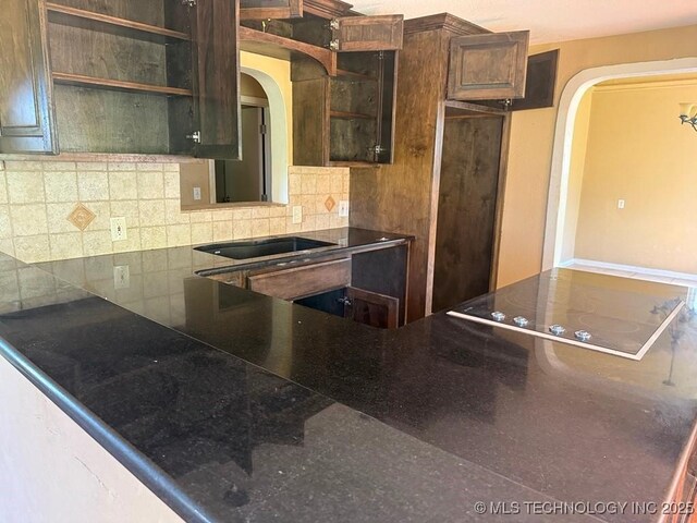 903 S Lynn Ln, Tulsa, OK 74108 - kitchen featuring arched walkways, black electric stovetop, backsplash, and glass insert cabinets