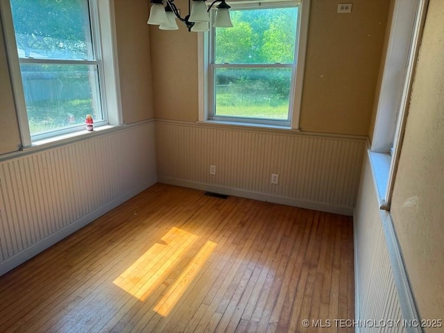 903 S Lynn Ln, Tulsa, OK 74108 - empty room featuring light wood-style flooring, wainscoting, plenty of natural light, and a chandelier