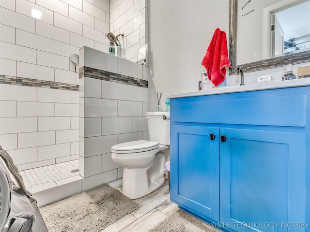23814 E 91st St S, Broken Arrow, OK 74014 - bathroom featuring vanity, a tile shower, toilet, a textured wall, and wood finished floors