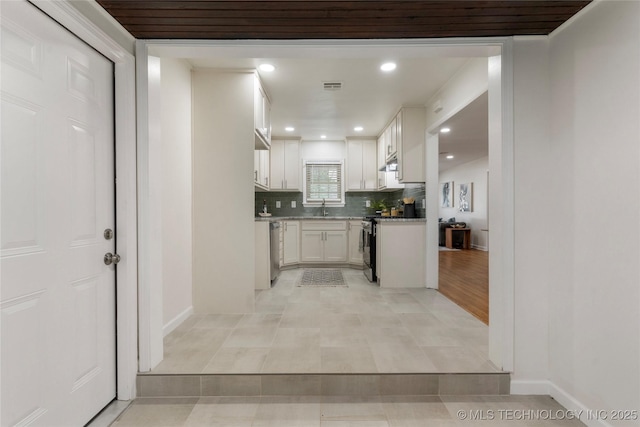 4514 S Quaker Ave, Tulsa, OK 74105 - kitchen featuring stainless steel appliances, a sink, white cabinets, backsplash, and baseboards