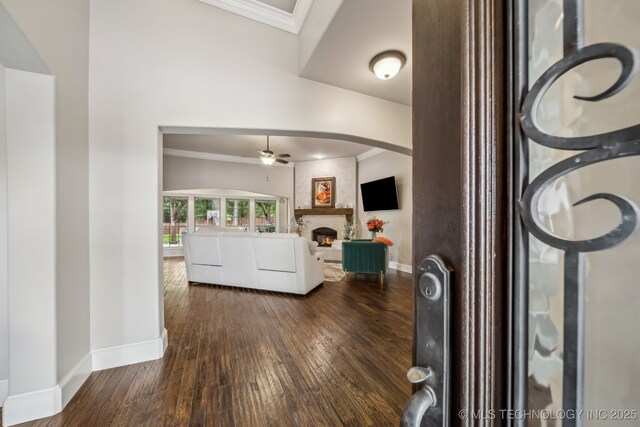 7734 S Indian Ave, Tulsa, OK 74132 - foyer entrance featuring a ceiling fan, dark wood-style flooring, a fireplace, baseboards, and crown molding