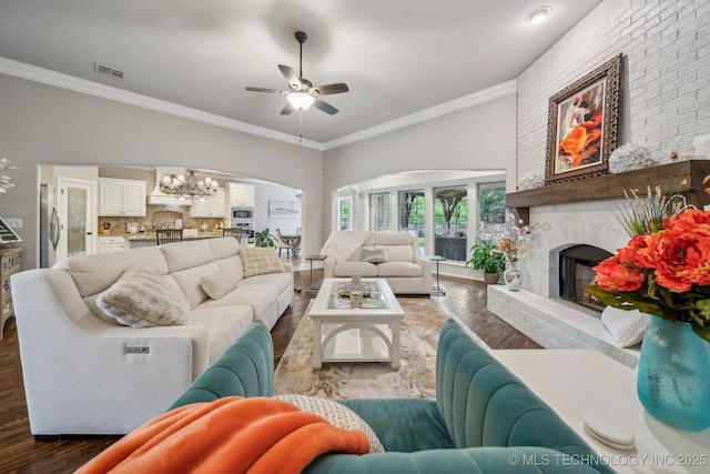 7734 S Indian Ave, Tulsa, OK 74132 - living room featuring a chandelier, ceiling fan, a brick fireplace, wood finished floors, and crown molding