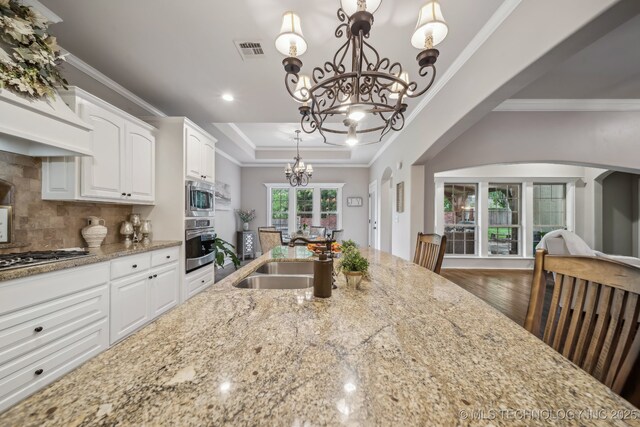 7734 S Indian Ave, Tulsa, OK 74132 - kitchen with a chandelier, a sink, appliances with stainless steel finishes, arched walkways, and light stone counters