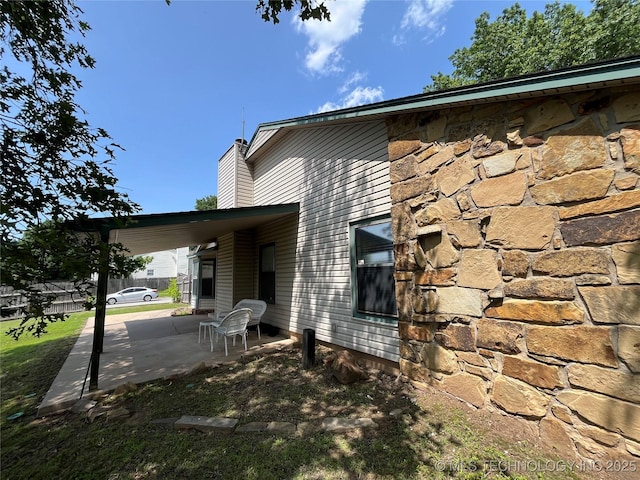 1700 S Cypress Ave, Broken Arrow, OK 74012 - view of property exterior with a patio area, stone siding, a chimney, and a carport