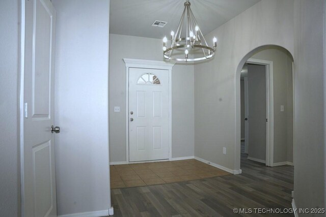 15310 E 89th Pl, Owasso, OK 74055 - foyer with arched walkways, a chandelier, dark wood-type flooring, and baseboards