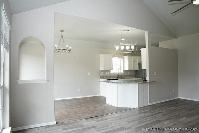 15310 E 89th Pl, Owasso, OK 74055 - kitchen featuring a chandelier, wood finished floors, vaulted ceiling, white cabinetry, and light stone countertops