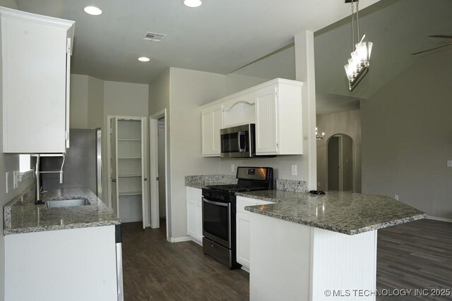 15310 E 89th Pl, Owasso, OK 74055 - kitchen with appliances with stainless steel finishes, a sink, a peninsula, dark wood-style floors, and arched walkways