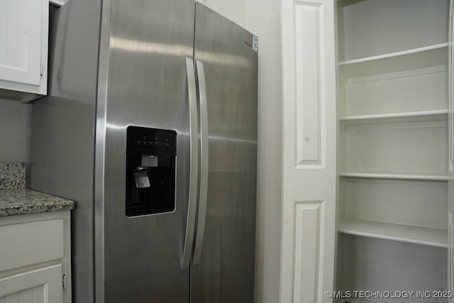 15310 E 89th Pl, Owasso, OK 74055 - detailed view of stainless steel refrigerator with ice dispenser, white cabinets, and light stone countertops