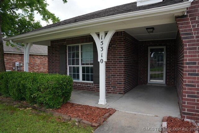 15310 E 89th Pl, Owasso, OK 74055 - view of exterior entry with brick siding and a shingled roof
