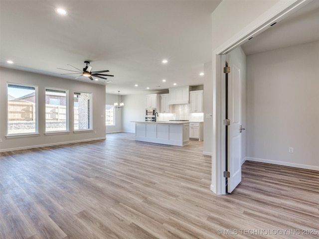 3011 S 6th Pl, Broken Arrow, OK 74012 - unfurnished living room featuring a ceiling fan, recessed lighting, light wood-style flooring, baseboards, and a chandelier