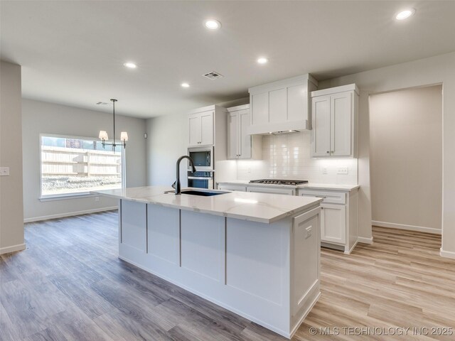 3011 S 6th Pl, Broken Arrow, OK 74012 - kitchen featuring a sink, custom range hood, stainless steel microwave, backsplash, and an island with sink