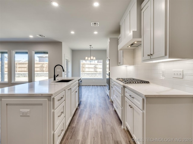 3011 S 6th Pl, Broken Arrow, OK 74012 - kitchen with a sink, custom exhaust hood, wood finished floors, white cabinets, and decorative backsplash