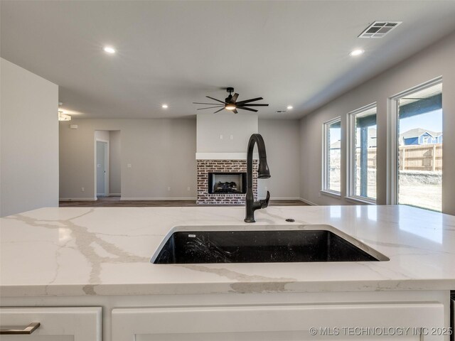 3011 S 6th Pl, Broken Arrow, OK 74012 - kitchen with a sink, recessed lighting, open floor plan, light stone counters, and white cabinets