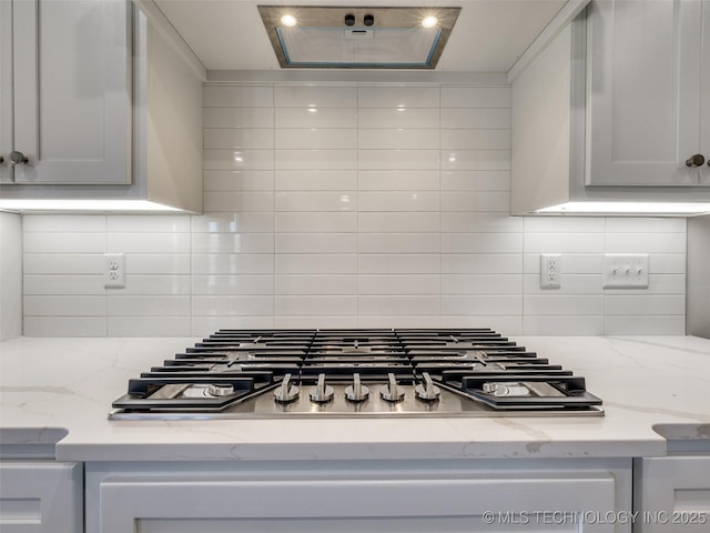 3011 S 6th Pl, Broken Arrow, OK 74012 - kitchen view of extractor fan, stainless steel gas cooktop, decorative backsplash, and light stone counters