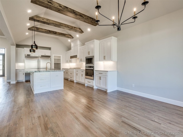 4010 W Baton Rouge St, Broken Arrow, OK 74011 - kitchen with stainless steel appliances, beamed ceiling, baseboards, a chandelier, and white cabinets