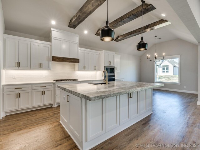 4010 W Baton Rouge St, Broken Arrow, OK 74011 - kitchen with a sink, stainless steel microwave, white cabinets, a center island with sink, and tasteful backsplash