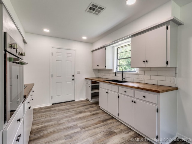703 NE 8th St, Wagoner, OK 74467 - kitchen featuring wood counters, a sink, light wood finished floors, recessed lighting, and decorative backsplash