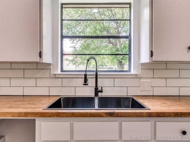 703 NE 8th St, Wagoner, OK 74467 - kitchen with a sink, white cabinetry, backsplash, and healthy amount of natural light