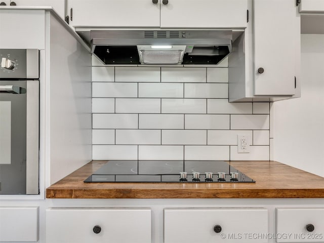 703 NE 8th St, Wagoner, OK 74467 - kitchen with ventilation hood, backsplash, stainless steel oven, black electric stovetop, and white cabinetry