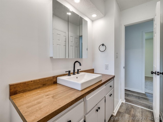 703 NE 8th St, Wagoner, OK 74467 - bathroom featuring vanity, wood finished floors, recessed lighting, and baseboards