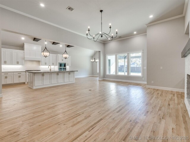 4011 W Baton Rouge St, Broken Arrow, OK 74011 - unfurnished living room featuring a chandelier, a fireplace, ornamental molding, light wood-style floors, and a sink