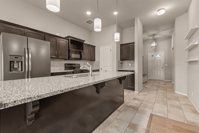 13010 E 122nd Pl, Collinsville, OK 74021 - kitchen with black microwave, dark brown cabinets, a sink, a breakfast bar, and light stone countertops
