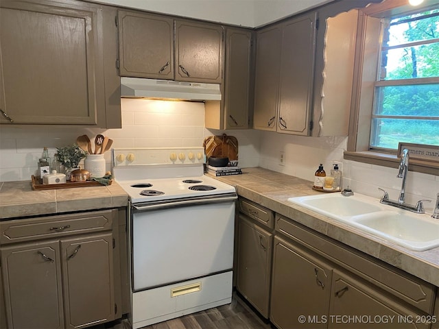 305 N 10th St, Hartshorne, OK 74547 - kitchen with white electric range oven, under cabinet range hood, decorative backsplash, gray cabinetry, and dark wood-style floors