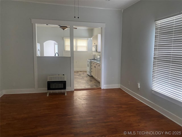 301 E Elm Ave, Eufaula, OK 74432 - unfurnished living room featuring heating unit, ceiling fan, dark wood-type flooring, baseboards, and ornamental molding