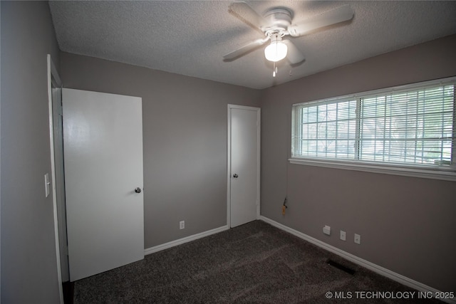 11612 E 28th St, Tulsa, OK 74129 - unfurnished bedroom with multiple windows, dark carpet, a textured ceiling, baseboards, and ceiling fan