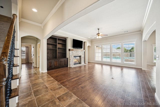 16210 E 49th St, Tulsa, OK 74134 - unfurnished living room with ceiling fan, ornamental molding, arched walkways, a fireplace, and baseboards