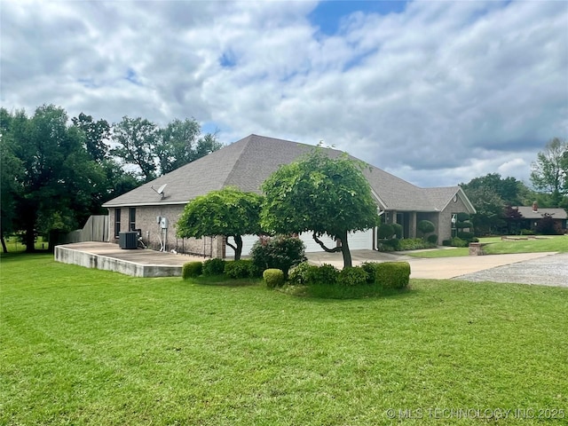 1403 NW Mimosa Cir, Stigler, OK 74462 - view of side of property with concrete driveway, central AC, a yard, and an attached garage