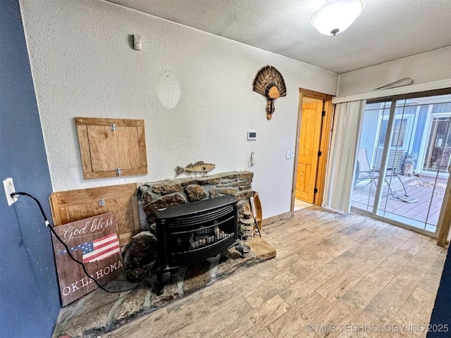 31663 S 530th Rd, Cookson, OK 74427 - living room with a wood stove, a textured wall, a textured ceiling, and light wood-style floors