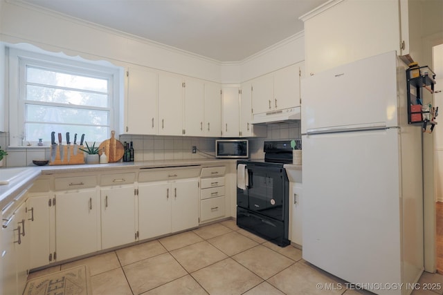 4524 E 45th St, Tulsa, OK 74135 - kitchen with freestanding refrigerator, black electric range oven, under cabinet range hood, stainless steel microwave, and white cabinetry