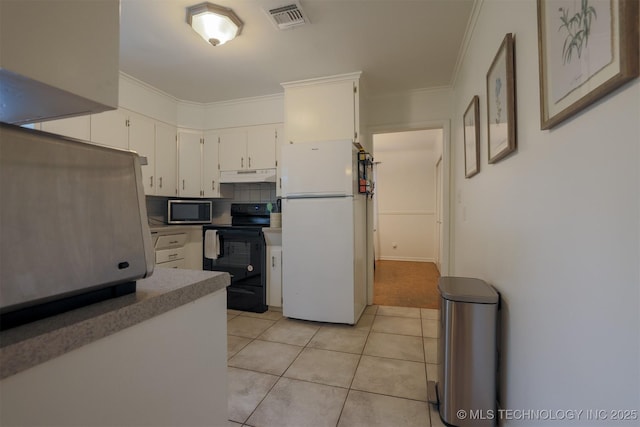 4524 E 45th St, Tulsa, OK 74135 - kitchen with freestanding refrigerator, black electric range, stainless steel microwave, under cabinet range hood, and light tile patterned floors
