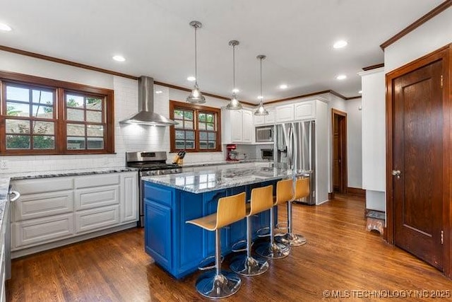 1701 S Rockford Ave, Tulsa, OK 74120 - kitchen featuring wall chimney range hood, appliances with stainless steel finishes, crown molding, white cabinets, and healthy amount of natural light