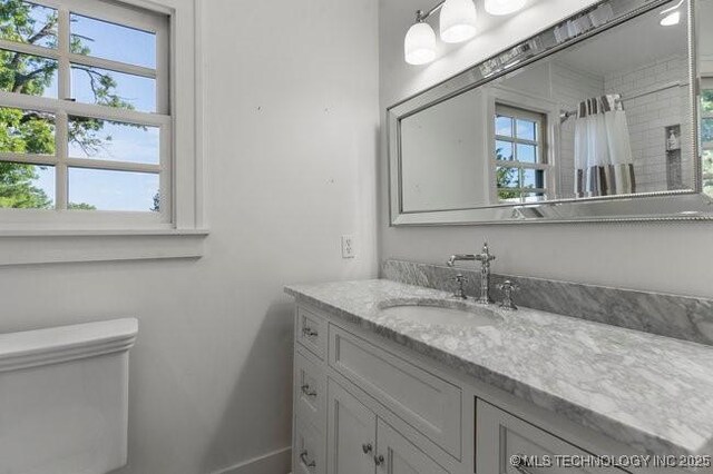 1701 S Rockford Ave, Tulsa, OK 74120 - full bathroom featuring vanity, toilet, baseboards, and a shower with curtain