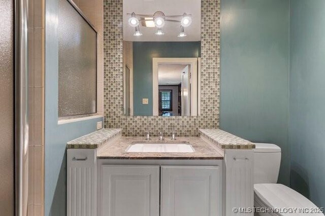 1701 S Rockford Ave, Tulsa, OK 74120 - bathroom with toilet, vanity, and backsplash