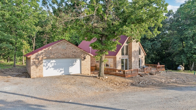 750 Spavinaw Hudson Pt, Spavinaw, OK 74366 - view of front facade with brick siding, driveway, an attached garage, a wooden deck, and metal roof