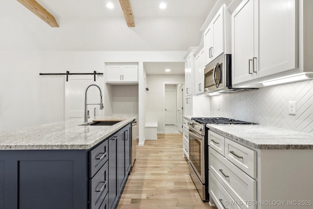 6512 N 27th St, Broken Arrow, OK 74014 - kitchen with stainless steel appliances, a sink, beamed ceiling, a barn door, and white cabinetry