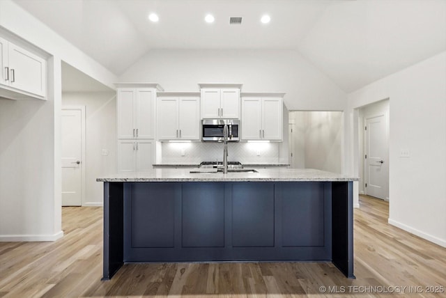 6512 N 27th St, Broken Arrow, OK 74014 - kitchen featuring stainless steel microwave, white cabinetry, tasteful backsplash, vaulted ceiling, and recessed lighting