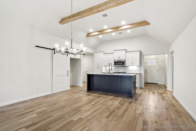 6512 N 27th St, Broken Arrow, OK 74014 - kitchen featuring stainless steel microwave, a barn door, a chandelier, white cabinetry, and a sink