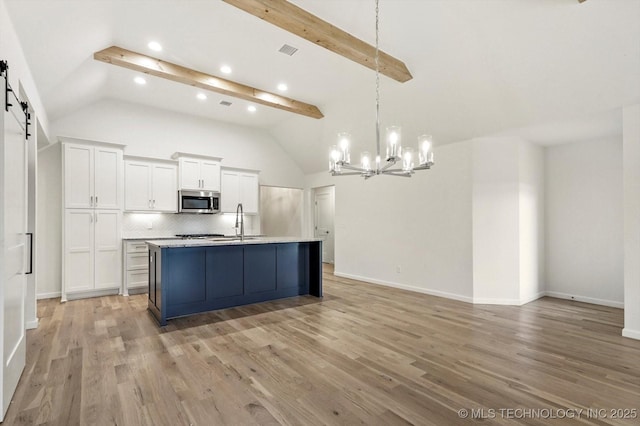 6512 N 27th St, Broken Arrow, OK 74014 - kitchen featuring stainless steel microwave, a chandelier, white cabinets, decorative backsplash, and a barn door