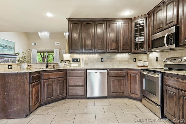 14355 N Trenton Ave, Skiatook, OK 74070 - kitchen featuring appliances with stainless steel finishes, backsplash, dark brown cabinets, light stone counters, and recessed lighting