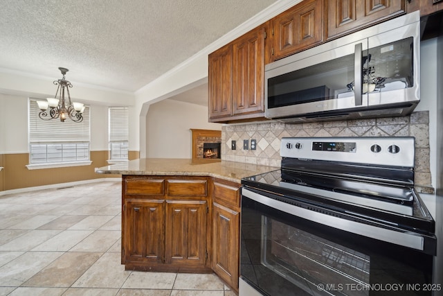 9227 S 95th E Ave, Tulsa, OK 74133 - kitchen featuring appliances with stainless steel finishes, a textured ceiling, backsplash, a chandelier, and brown cabinetry