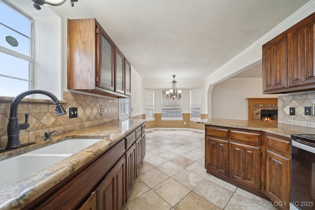 9227 S 95th E Ave, Tulsa, OK 74133 - kitchen featuring a sink, a chandelier, electric range, tasteful backsplash, and a fireplace