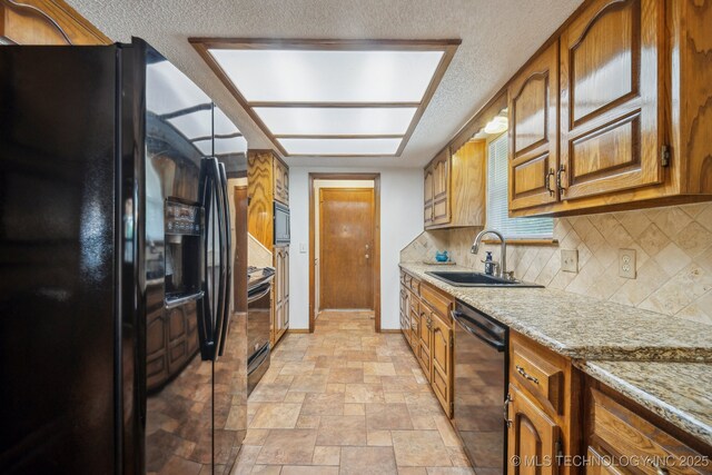 2630 W Boston Pl, Broken Arrow, OK 74012 - kitchen with black appliances, a sink, decorative backsplash, brown cabinets, and light stone counters