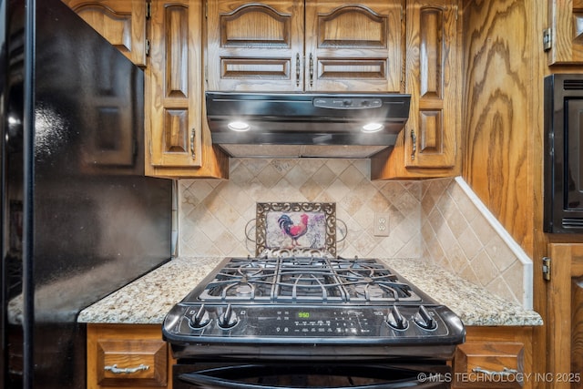 2630 W Boston Pl, Broken Arrow, OK 74012 - kitchen with black appliances, under cabinet range hood, brown cabinets, and decorative backsplash