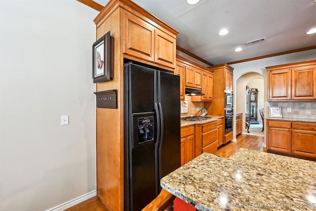 11715 S 93rd E Ave, Bixby, OK 74008 - kitchen with black fridge with ice dispenser, arched walkways, under cabinet range hood, recessed lighting, and decorative backsplash